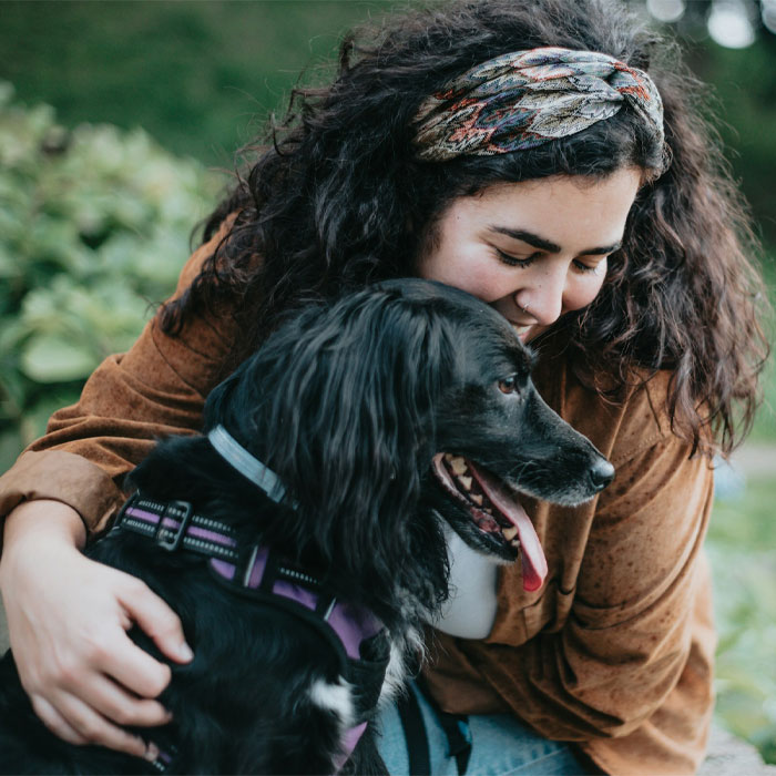 A black dog being hugged by its owner
